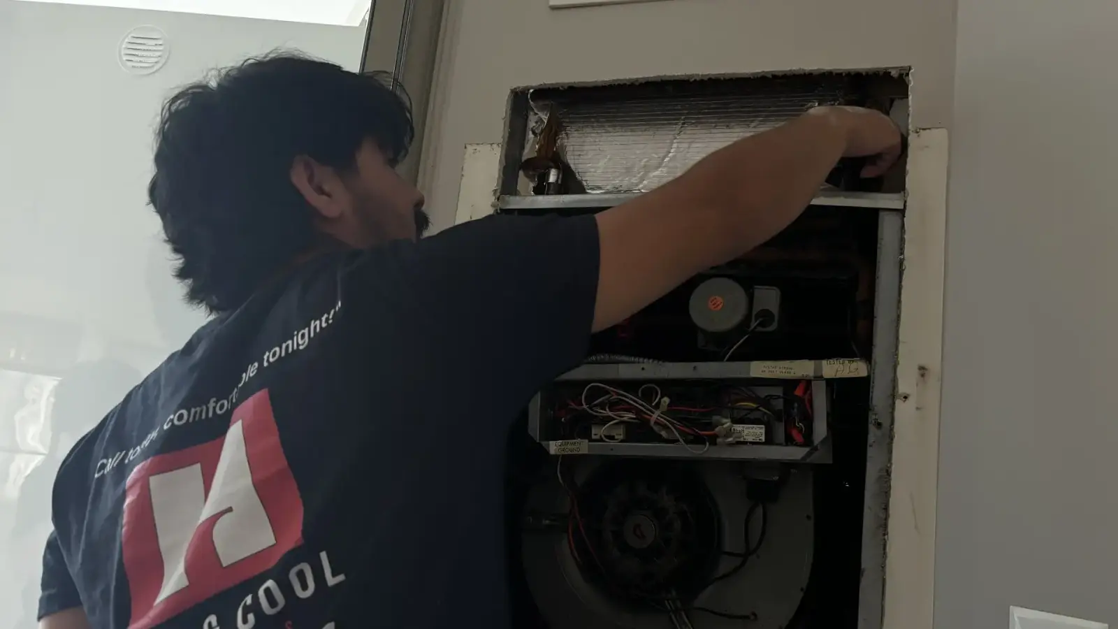 Hot & Cool Services technician inspecting the internal components of a residential gas furnace
